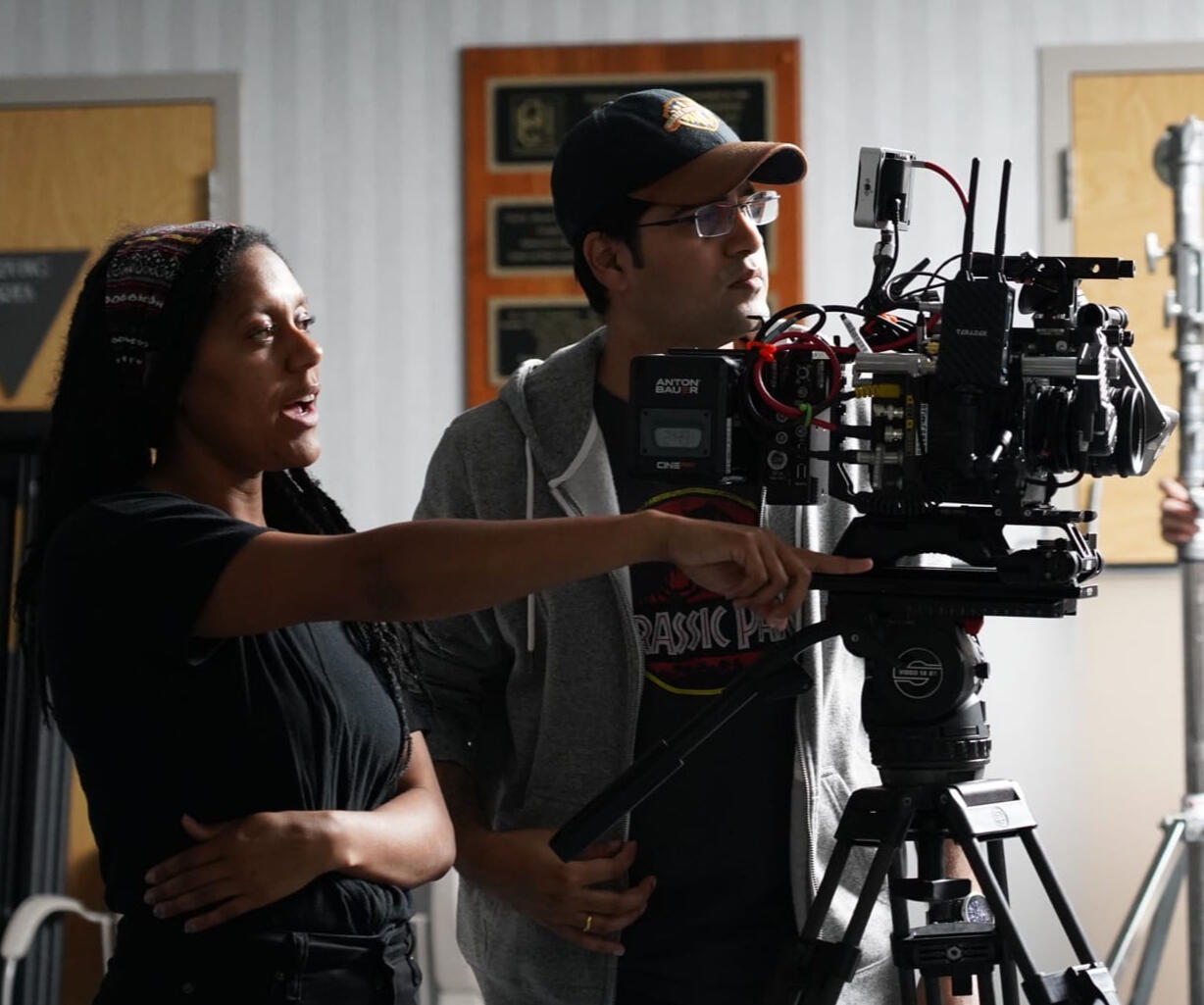 Cephra a black woman with locs stares excitedly into the monitor as her DP as hard at work in the background